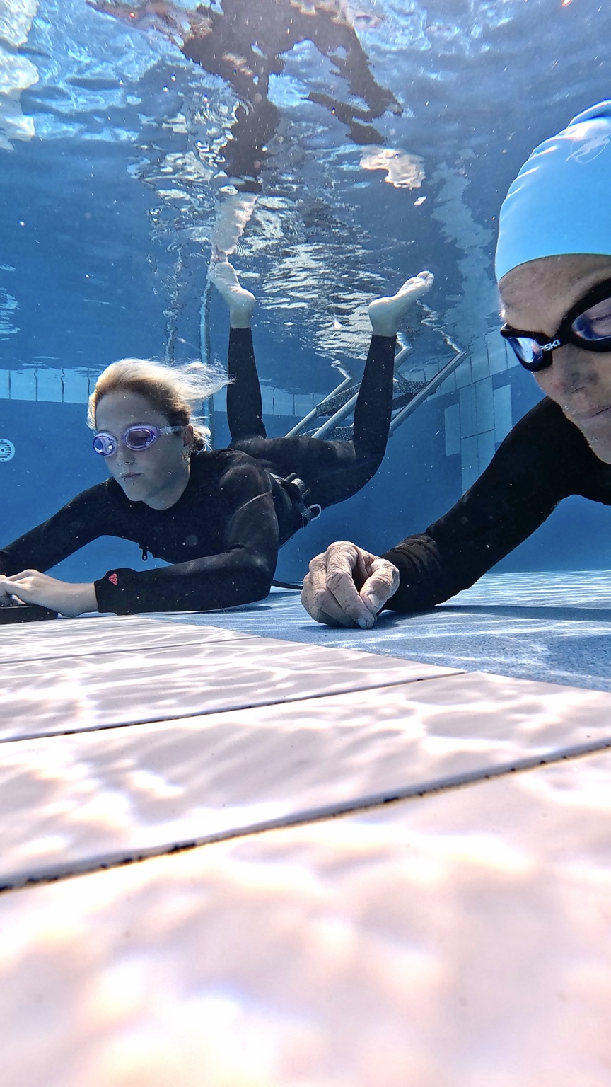 Heli coaching a participant during a calm underwater pool session
