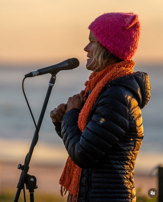 Heli Murray speaking outdoors at sunset