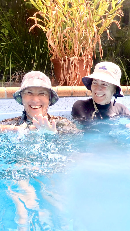 Two women laughing together in the pool during a Surf Apnea workshop